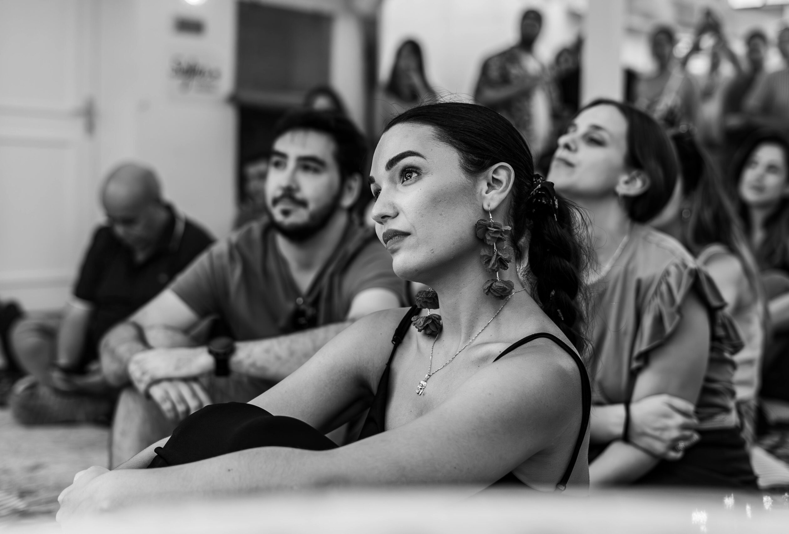 A group of adults attentively sitting indoors, captured in a black and white photo.