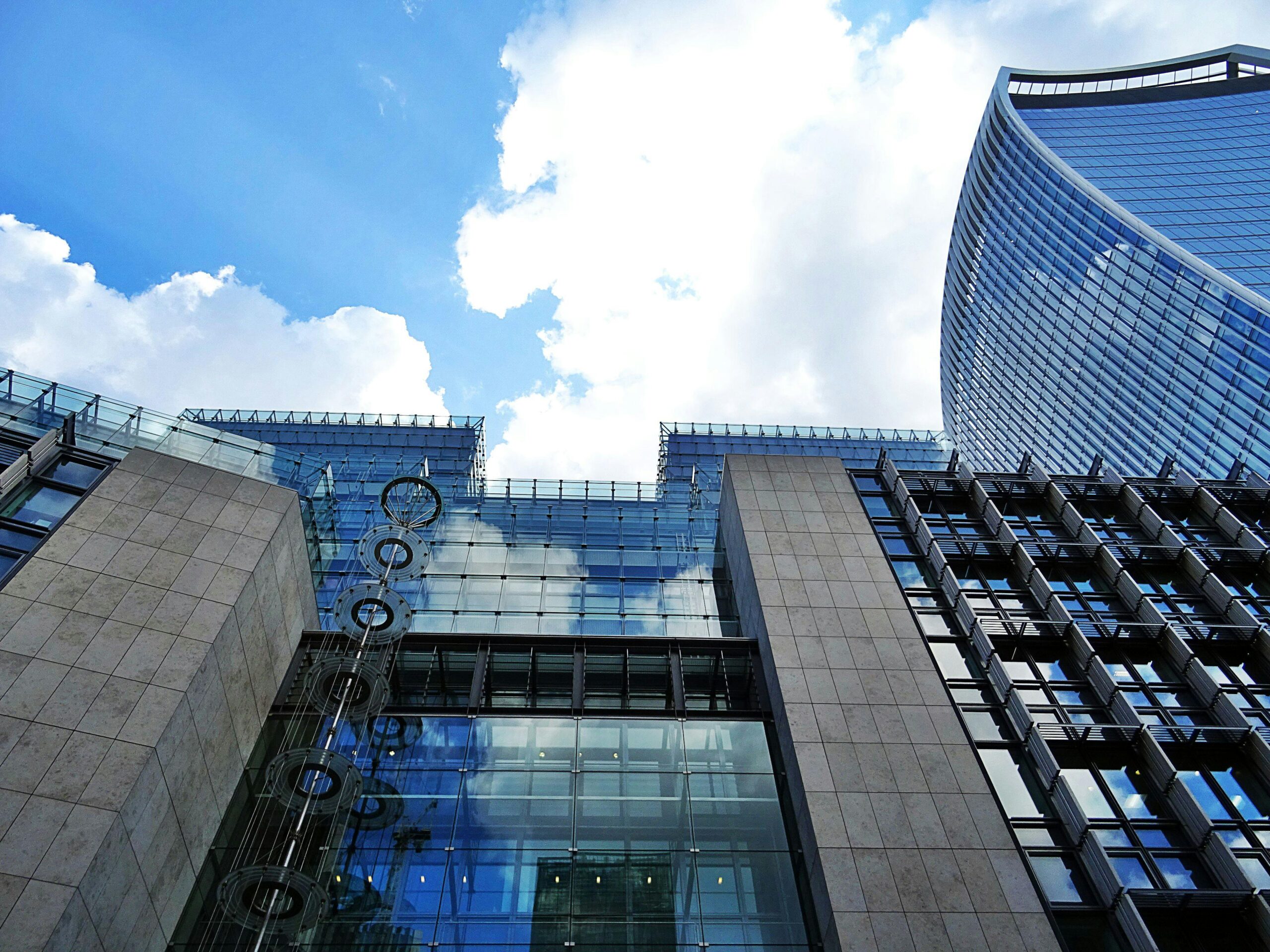 Futuristic glass and steel skyscraper with reflections against a bright blue sky.